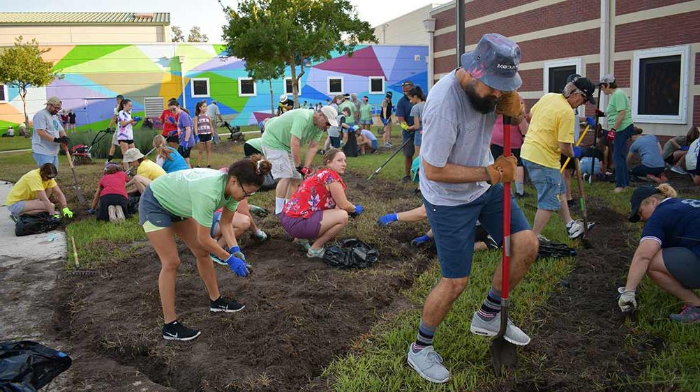 澳门足彩app team members landscaping the front of a middle school.